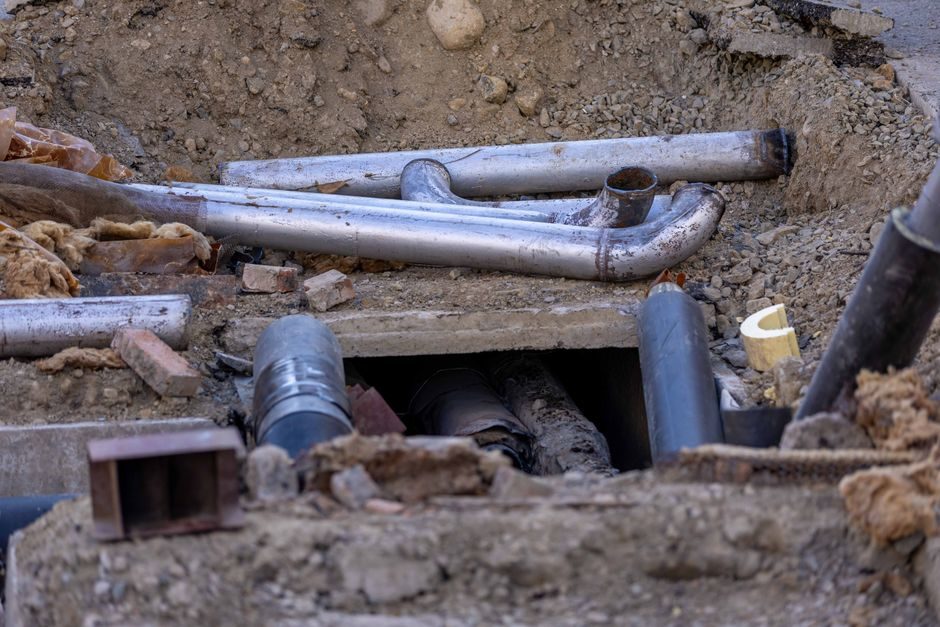 Close-up of urban pipe installation at a construction site, showing various pipes and materials.